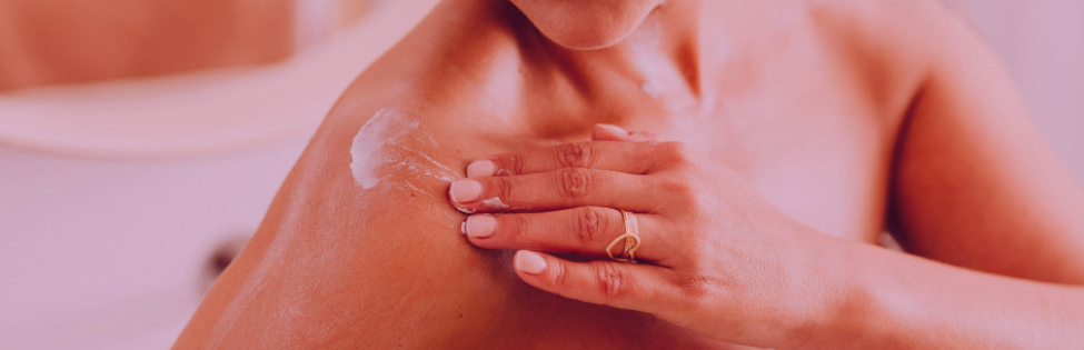 Person applying sunscreen to their shoulder for sun protection.